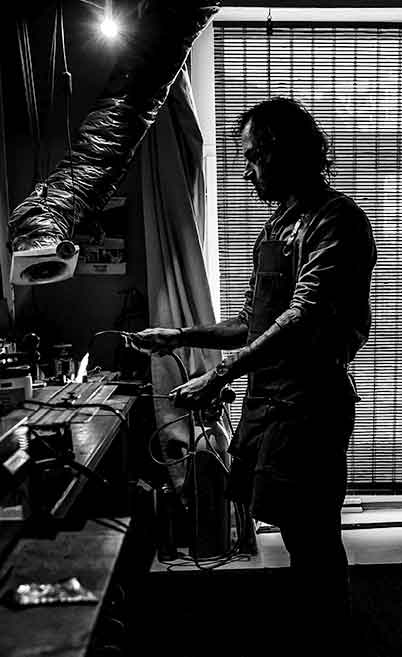 Sébastien au chalumeau en contre jour dans son atelier